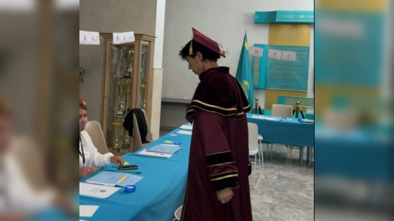 Студент академиялық мантиясымен сайлау учаскесіне дауыс беруге келді